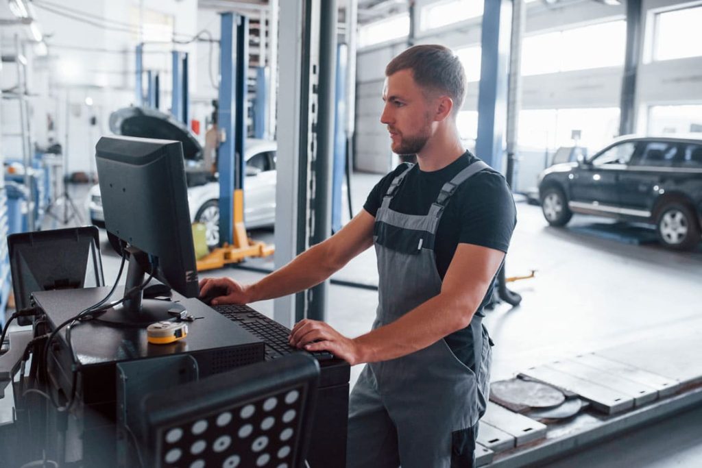 automotive technician reviewing warranty claims on a desktop computer