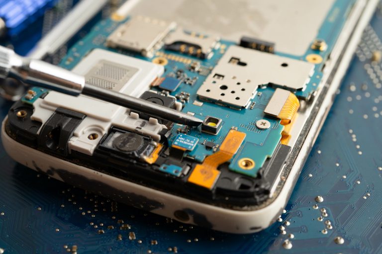 A close-up of a smartphone with its back cover removed, revealing internal components, during a repair process